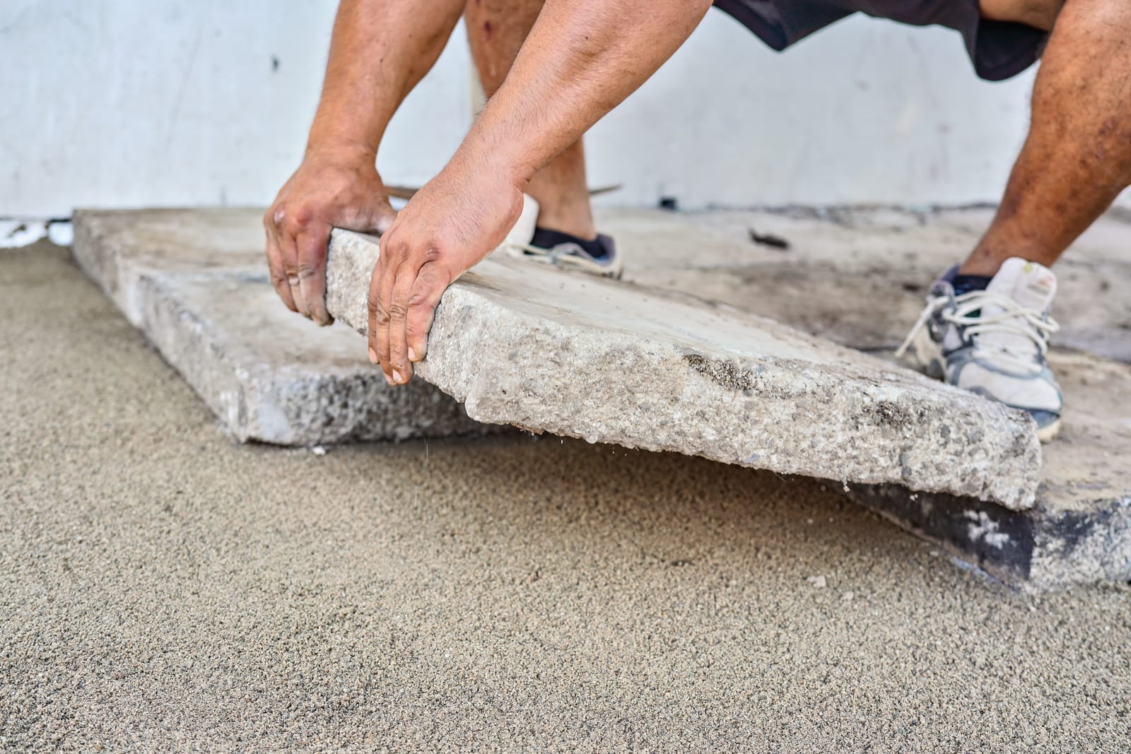 52689486_installing-new-pavement-or-floor-outside-from-large-concrete-tiles-closeup-detail-on-male-worker-fitting-stone-block-over-sand-and-gravel-base-layer.jpg